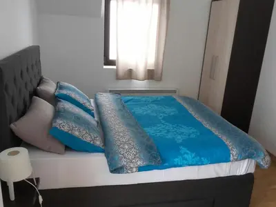 a bed with blue sheets and pillows in a bedroom at Dvori Apartments in Kopaonik