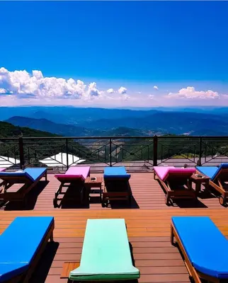 a deck with chairs and tables on top of a mountain at Modern Lux Apartment H8 at Milmari Resort in Kopaonik