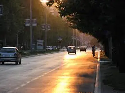 a street with cars driving down a road with lights at Blue New Yorker in Niš