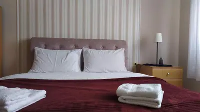 a bedroom with a bed with two towels on it at Community Park Apartment in Niš