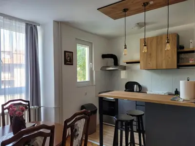 a kitchen with a counter and some chairs in it at Community Park Apartment in Niš
