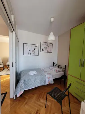 a bedroom with a bed and a chair in it at Community Park Apartment in Niš