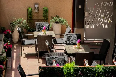 an outdoor patio with tables and chairs and flowers at Bed and Breakfast Majesty in Niš
