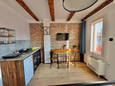 a kitchen with a counter and a table in a room at Apartment By the River in Niš