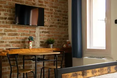 a kitchen with a wooden table and a brick wall at Apartment By the River in Niš