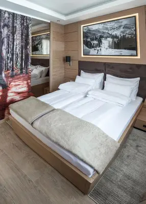 a bedroom with a large bed with white sheets at Apart Hotel Mamut in Kopaonik