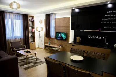 a living room with a table and a tv in it at Apart Hotel Mamut in Kopaonik