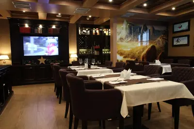 a dining room with tables and chairs and a television at Apart Hotel Mamut in Kopaonik