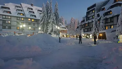 a street covered in snow in front of buildings at Apartman Jelač Konaci in Kopaonik