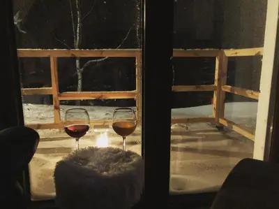 two glasses of wine sitting in front of a window at Chalet Vrhovi Kopaonika in Kopaonik