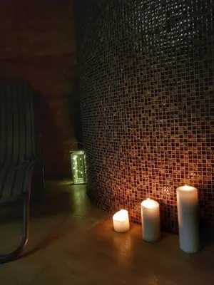 two candles sitting on the floor next to a brick wall at Chalet Vrhovi Kopaonika in Kopaonik