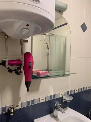 a bathroom with a sink and a mirror and a hair dryer at Apartmani Mićić in Vrnjačka Banja