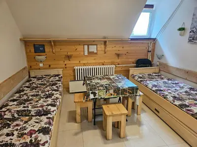a room with two beds and a table and chairs at apartman na stazi in Kopaonik