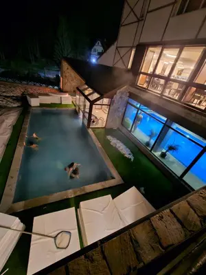 two people swimming in a swimming pool at night at Ebra Kraljevi Čardaci Kopaonik in Kopaonik