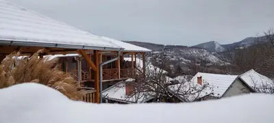 a house covered in snow with mountains in the background at Golemi kamik Pirot in Pirot