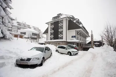two cars parked in the snow in front of a building at Zupa Deluxe Kopaonik in Kopaonik