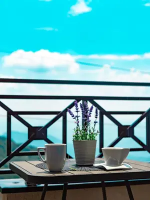 a table with two cups and flowers on a balcony at Apartman Sunset Milmari Kopaonik M10 in Kopaonik