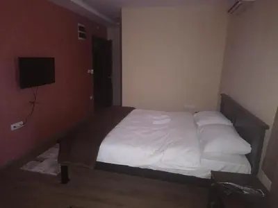 a bedroom with a bed with white sheets and a television at Prenoćište HRAST in Paraćin