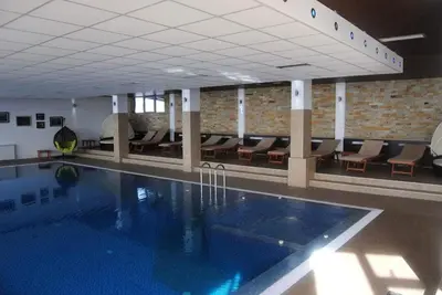 a large swimming pool in a building with chairs at Apartment M1 MEGI, Milmari Resort in Kopaonik