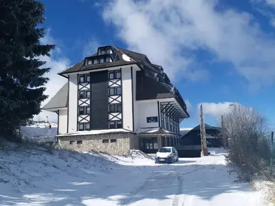 a large building with a car parked in the snow at Apartmani ŽUPA in Kopaonik