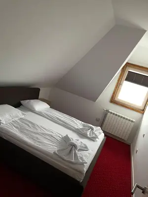 a bedroom with a white bed with a window at Apartmani ŽUPA in Kopaonik