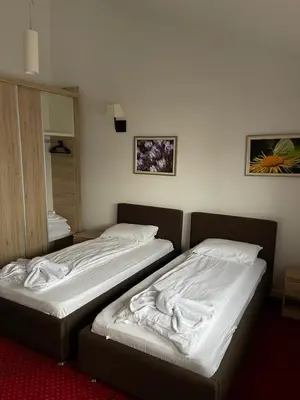 two beds in a hotel room with white sheets at Apartmani ŽUPA in Kopaonik