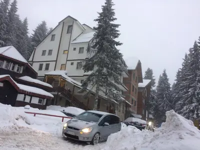 a car parked in the snow in front of a building at Apartment Lazic vila Suri in Kopaonik