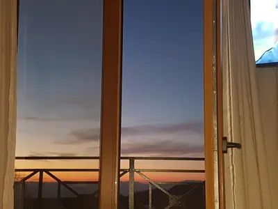 an open window with a view of a sunset at LUX Apartman B1 Milmari in Kopaonik