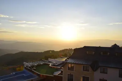 a view of a house with the sun in the background at LUX Apartman B1 Milmari in Kopaonik