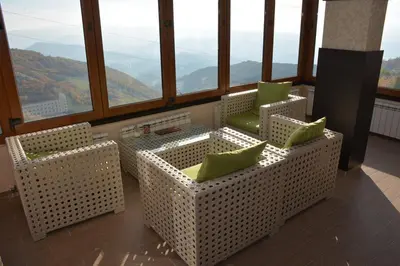 a room with two chairs and a table and windows at LUX Apartman B1 Milmari in Kopaonik