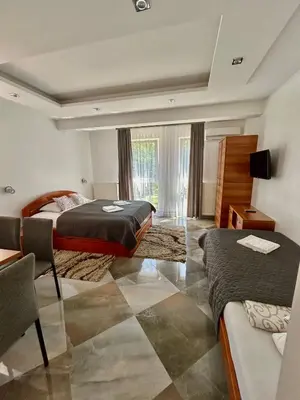 a hotel room with two beds and a table at Vila Markovic-a in Soko Banja