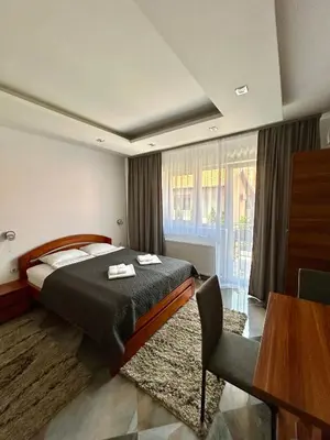 a bedroom with a bed and a table and a window at Vila Markovic-a in Soko Banja