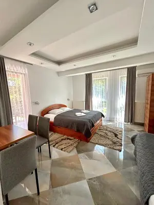 a bedroom with a bed and a table and some windows at Vila Markovic-a in Soko Banja