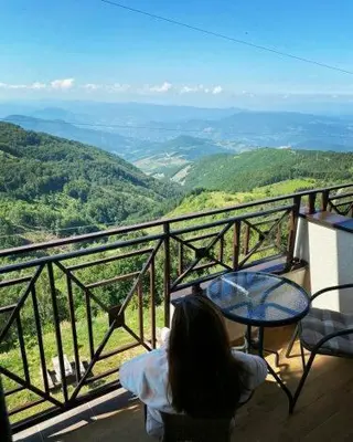 a woman sitting at a table on a balcony with a view at Milmari M18 Kopaonik in Kopaonik