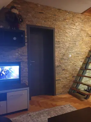 a living room with a television and a brick wall at kraljevski apartman in Kopaonik