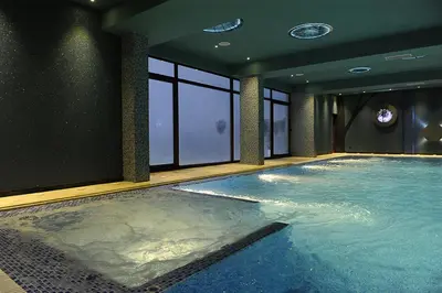 a large swimming pool in a room with windows at kraljevski apartman in Kopaonik