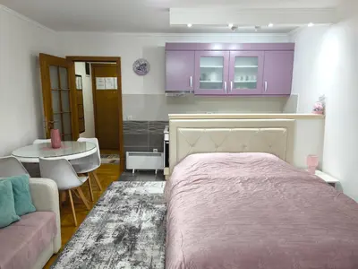 a bedroom with a bed and a table and purple cabinets at Alex 2 apartman in Vrnjačka Banja