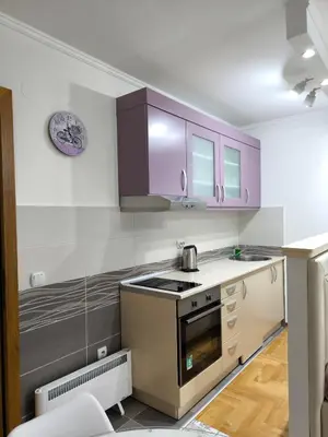 a kitchen with purple cabinets and a stove top oven at Alex 2 apartman in Vrnjačka Banja