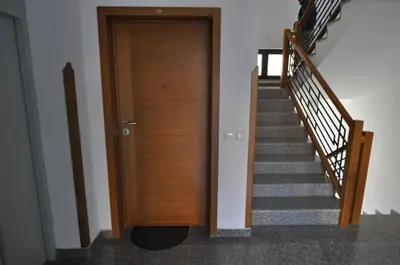 a hallway with a wooden door and stairs at Alex 2 apartman in Vrnjačka Banja