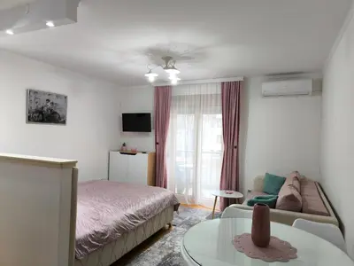 a bedroom with a bed and a couch and a table at Alex 2 apartman in Vrnjačka Banja