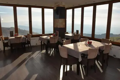 a restaurant with tables and chairs and large windows at Apartment Simonida - Milmari M3 in Kopaonik