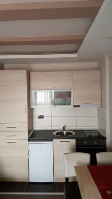 a kitchen with white cabinets and a black counter top at Apartment Simonida - Milmari M3 in Kopaonik