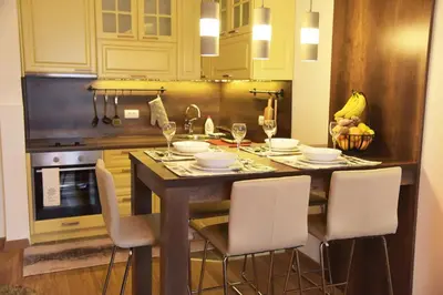 a kitchen with a table with chairs and wine glasses at Apartment Mint in Kopaonik