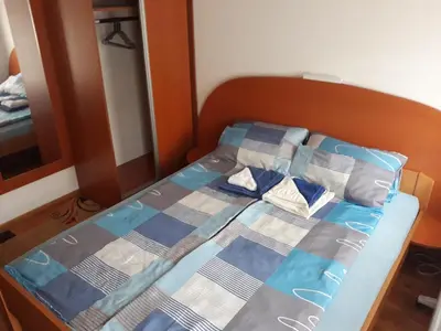 a bed with a blue and gray quilt on it at Apartment Hedonic in Vrnjačka Banja