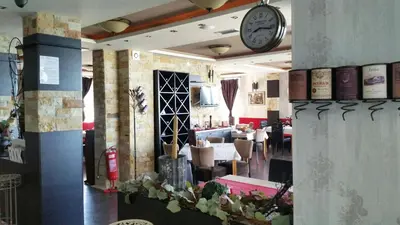 a restaurant with a clock on the wall and tables at Shining Apartment Milmari M11 in Kopaonik