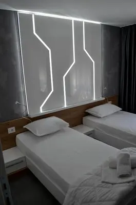 two beds in a room with lights on the wall at Apartments Good Night in Niš