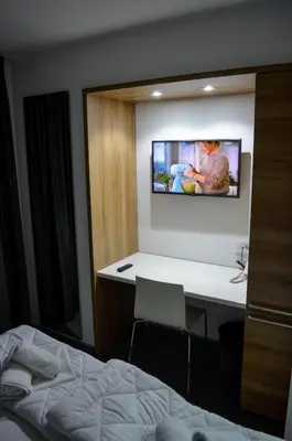a bedroom with a bed and a tv on the wall at Apartments Good Night in Niš