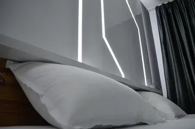 two white pillows sitting on a bed next to a window at Apartments Good Night in Niš