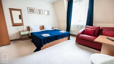 a bedroom with a bed and a red couch at Apartments Passage in Vrnjačka Banja