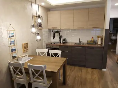 a kitchen with a wooden table and white chairs at Apartman Dragana Kopaonik in Kopaonik
